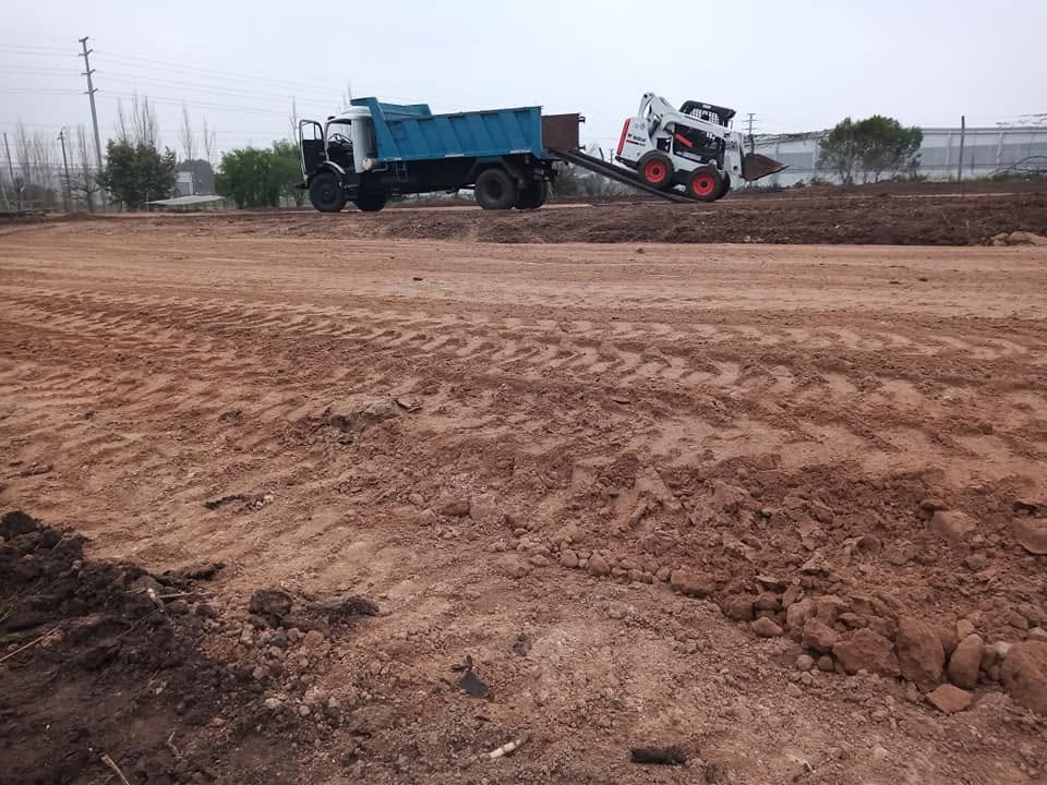 Camión volcador y minicargadora nivelando un terreno
