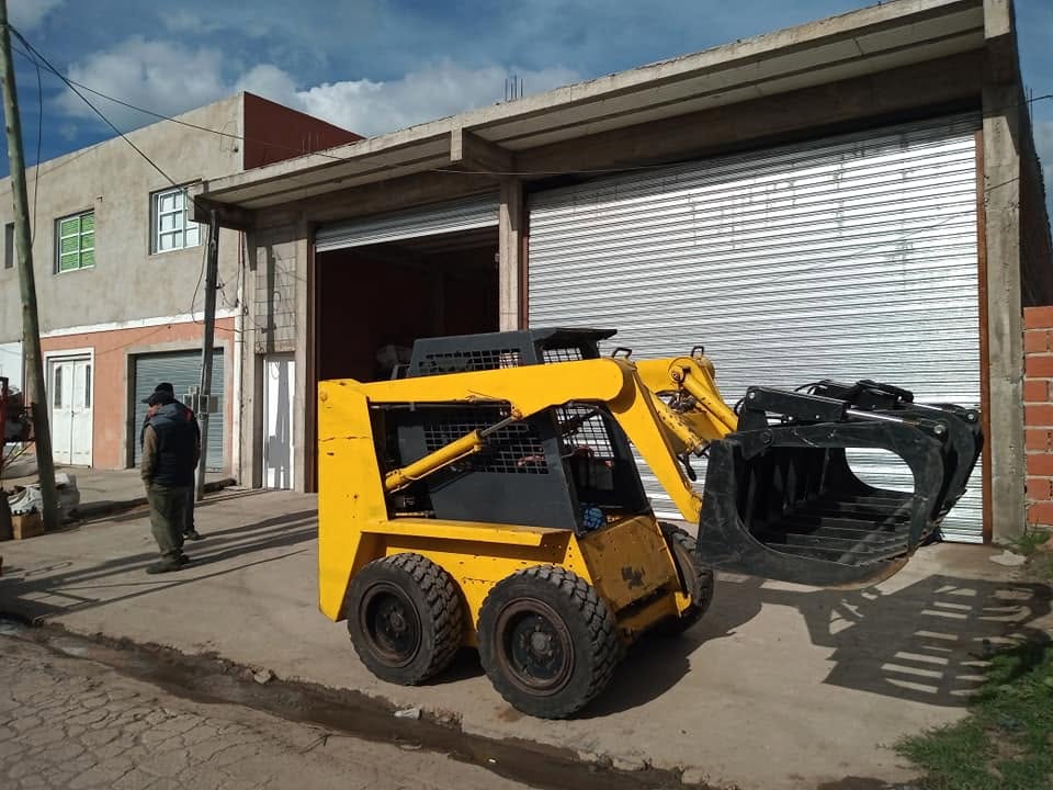 Minicargadora amarilla con pinza en el galpón de DDS Vial